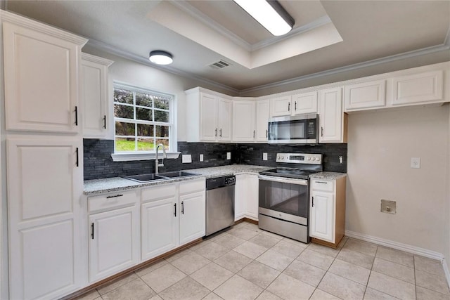 kitchen featuring white cabinetry, sink, a tray ceiling, light tile patterned floors, and appliances with stainless steel finishes