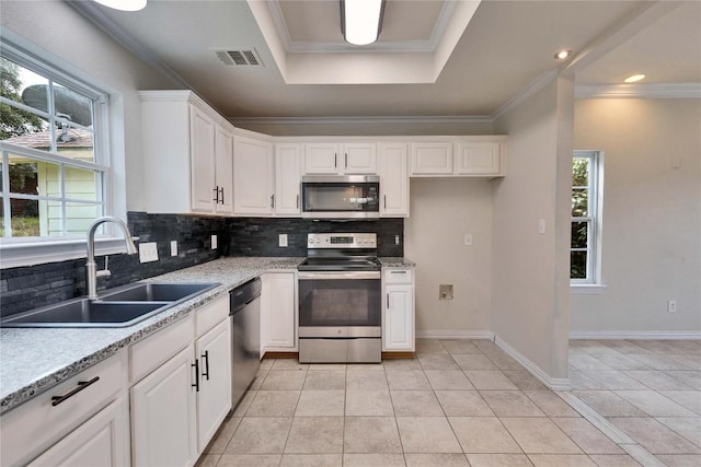 kitchen with appliances with stainless steel finishes, a raised ceiling, sink, white cabinetry, and light tile patterned flooring