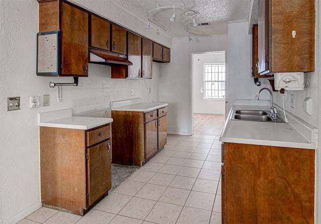 kitchen with light tile patterned floors, a textured ceiling, crown molding, and sink