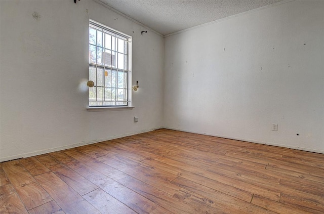 empty room featuring crown molding, a textured ceiling, and light hardwood / wood-style flooring