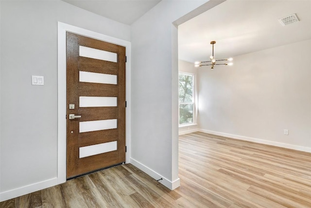 foyer with light wood-type flooring and an inviting chandelier