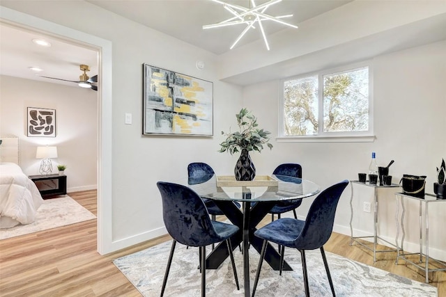 dining space featuring ceiling fan with notable chandelier and hardwood / wood-style flooring