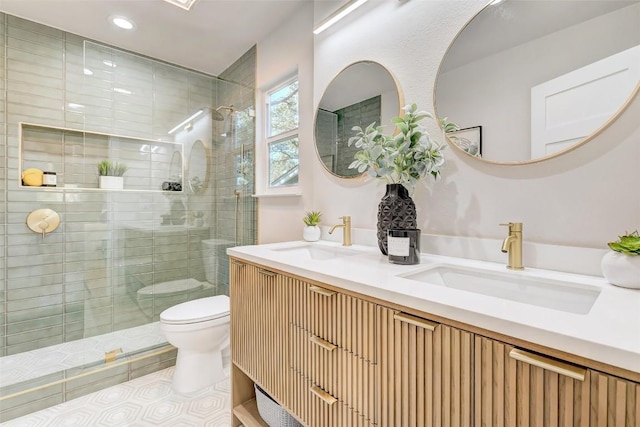 bathroom featuring tile patterned flooring, vanity, toilet, and tiled shower