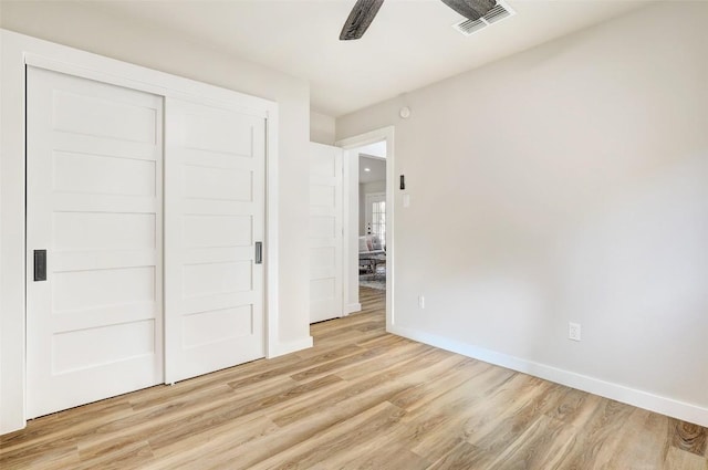 unfurnished bedroom with ceiling fan, light wood-type flooring, and a closet