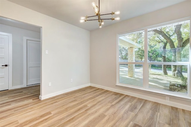 empty room featuring a chandelier and light hardwood / wood-style floors