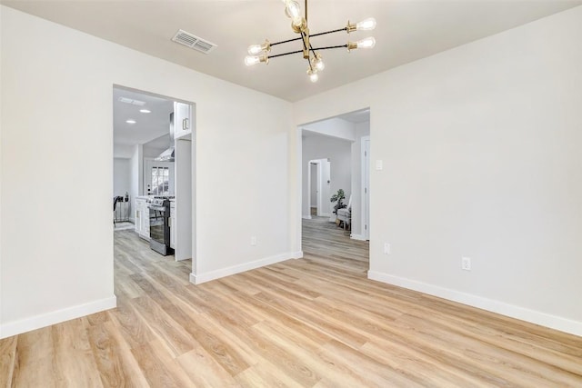 unfurnished room with light hardwood / wood-style flooring and a notable chandelier