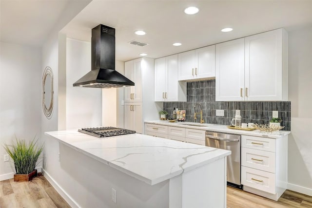 kitchen featuring appliances with stainless steel finishes, light wood-type flooring, sink, exhaust hood, and white cabinets