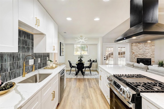 kitchen with sink, light hardwood / wood-style flooring, wall chimney exhaust hood, white cabinetry, and stainless steel appliances