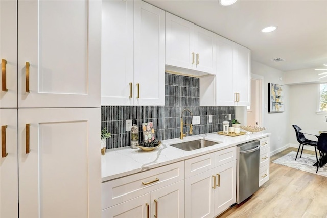 kitchen with sink, light hardwood / wood-style flooring, stainless steel dishwasher, light stone counters, and white cabinetry