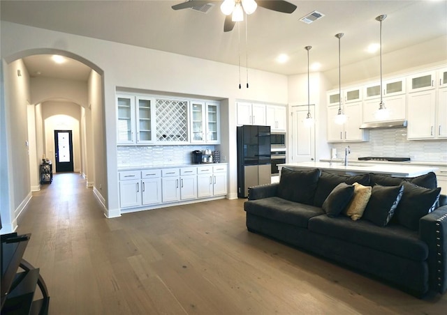 living room featuring hardwood / wood-style flooring, ceiling fan, and sink