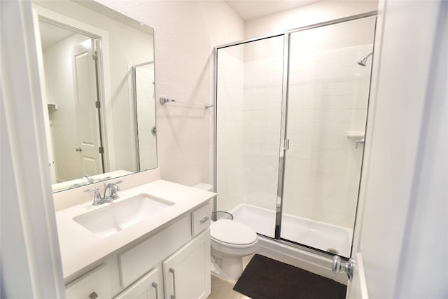 bathroom featuring a shower with door, vanity, and toilet