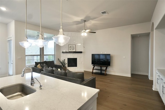 kitchen with pendant lighting, dark wood-type flooring, white cabinets, sink, and light stone countertops