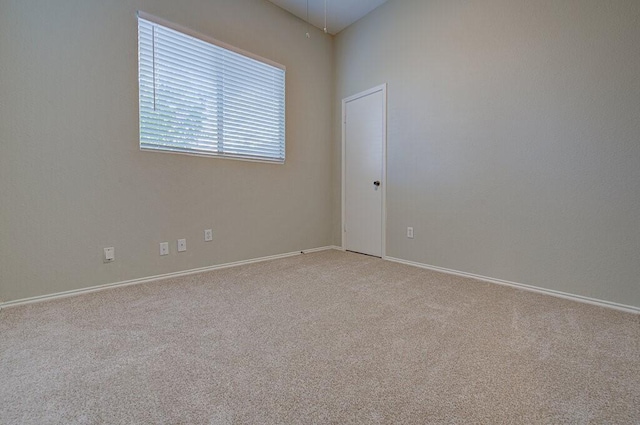 empty room featuring baseboards and light carpet