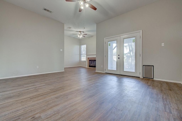 unfurnished living room with a glass covered fireplace, wood finished floors, french doors, and visible vents