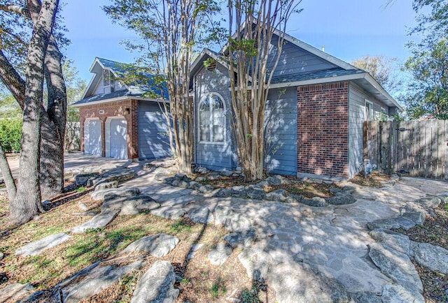 view of front of home featuring an attached garage, fence, and brick siding