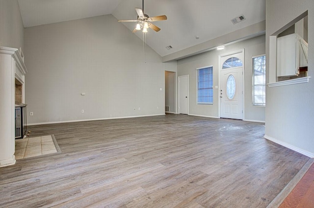 unfurnished living room featuring a ceiling fan, baseboards, visible vents, high vaulted ceiling, and light wood-type flooring