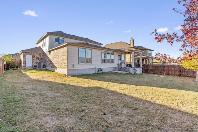 back of house with central AC unit and a yard