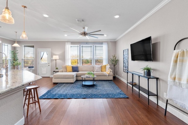 living room featuring ceiling fan, ornamental molding, and dark wood-type flooring