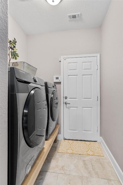 laundry room with washer and dryer and light tile patterned flooring