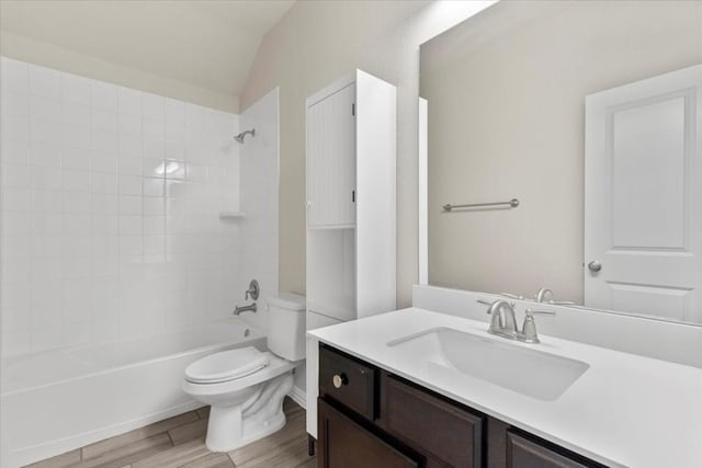 full bathroom featuring vanity, tiled shower / bath, vaulted ceiling, hardwood / wood-style flooring, and toilet