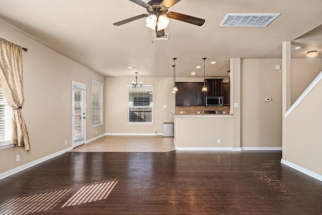 unfurnished living room featuring ceiling fan with notable chandelier and dark hardwood / wood-style floors