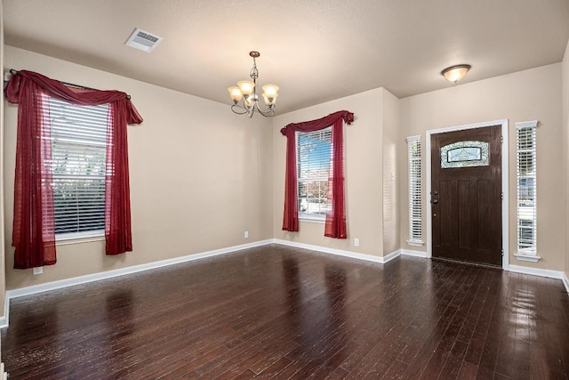 foyer with dark wood-type flooring and a notable chandelier