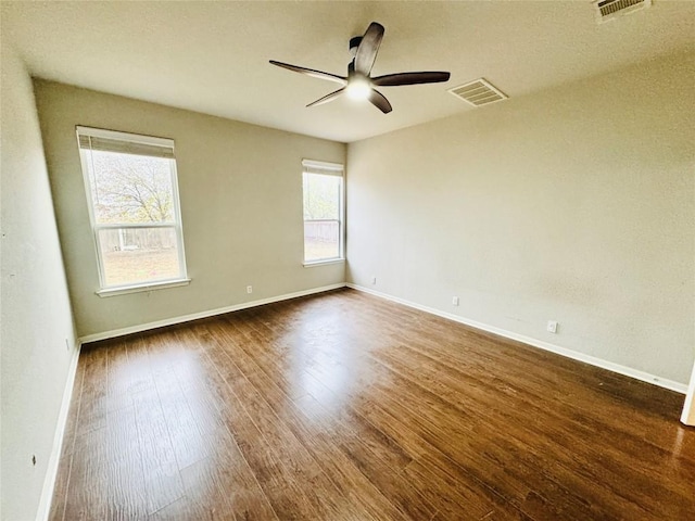 spare room with a wealth of natural light, ceiling fan, and dark hardwood / wood-style floors