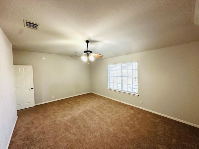 spare room featuring dark colored carpet and ceiling fan