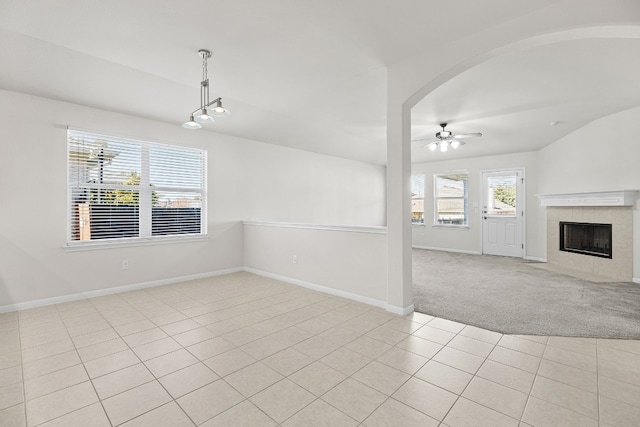 unfurnished living room featuring ceiling fan, light tile patterned flooring, lofted ceiling, and a fireplace