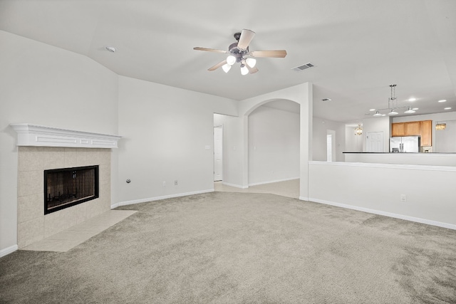 unfurnished living room with ceiling fan, a fireplace, light colored carpet, and lofted ceiling