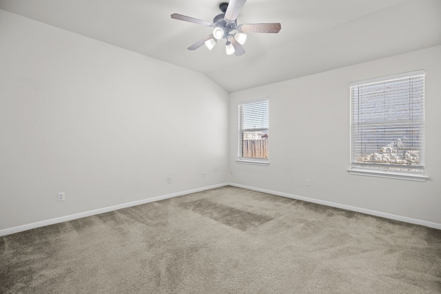 carpeted empty room featuring a wealth of natural light, ceiling fan, and vaulted ceiling