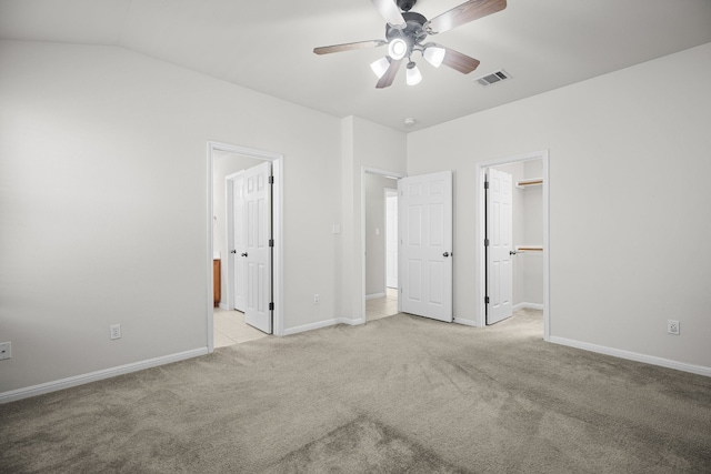 unfurnished bedroom with ceiling fan, ensuite bathroom, light colored carpet, a walk in closet, and a closet