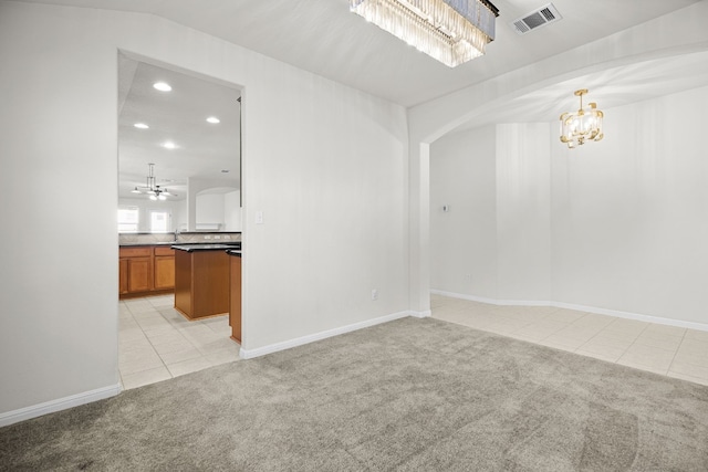 unfurnished room featuring ceiling fan with notable chandelier and light carpet