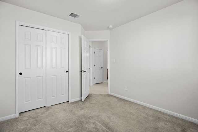 unfurnished bedroom with light colored carpet and a closet