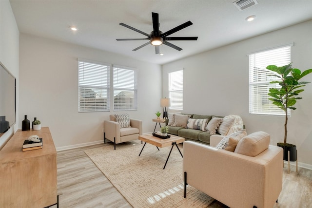 living room featuring plenty of natural light, ceiling fan, and light wood-type flooring