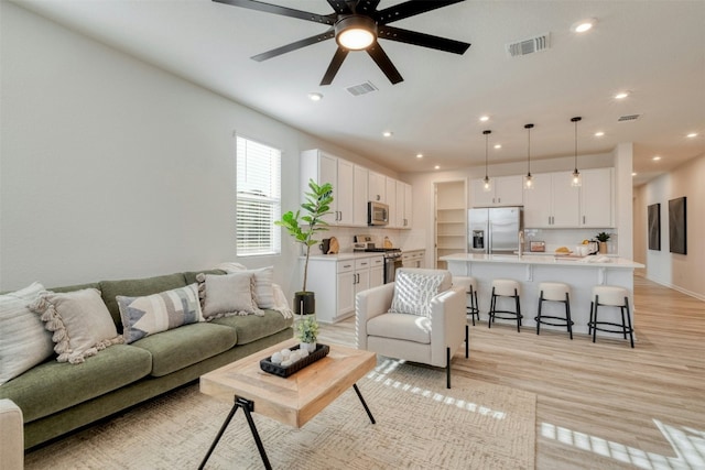 living room with ceiling fan and light wood-type flooring