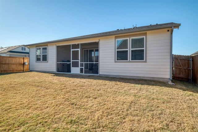 rear view of house featuring a sunroom and a yard