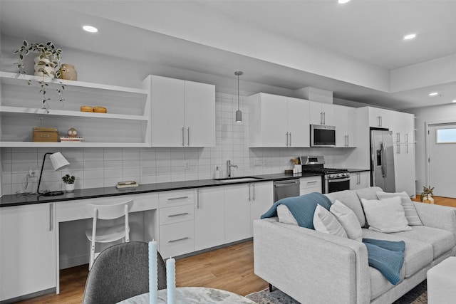 kitchen with sink, stainless steel appliances, decorative backsplash, white cabinets, and decorative light fixtures