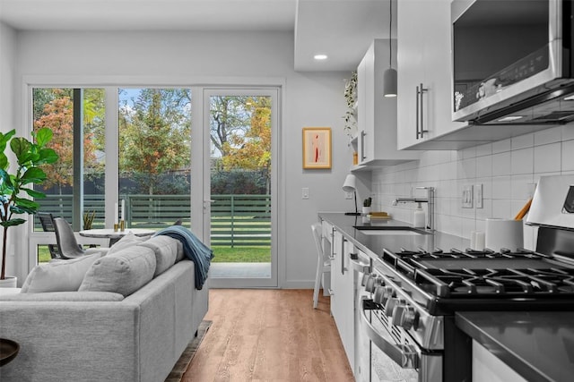 kitchen with appliances with stainless steel finishes, white cabinetry, sink, plenty of natural light, and light hardwood / wood-style flooring