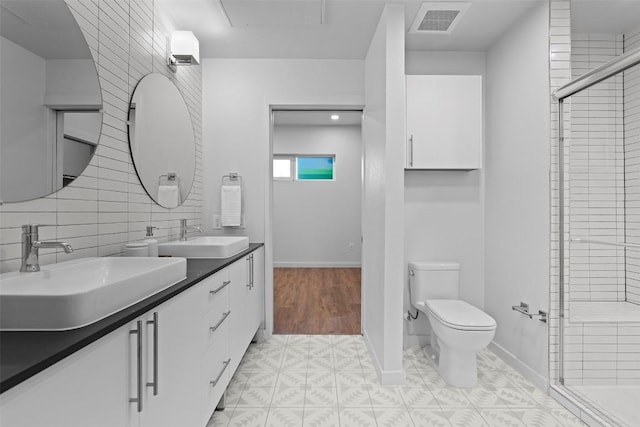 bathroom featuring vanity, a shower with shower door, tile walls, and toilet