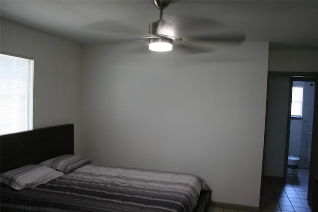 tiled bedroom with connected bathroom, multiple windows, and ceiling fan