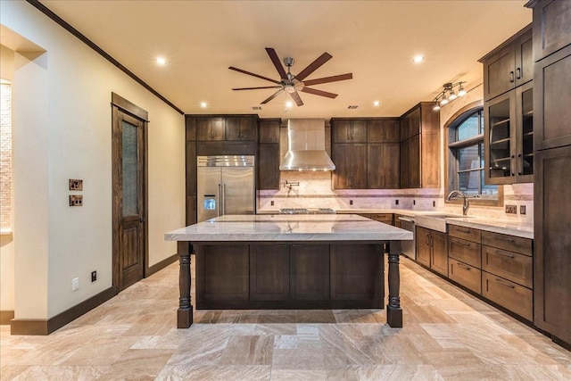 kitchen featuring sink, backsplash, a center island, stainless steel appliances, and wall chimney range hood