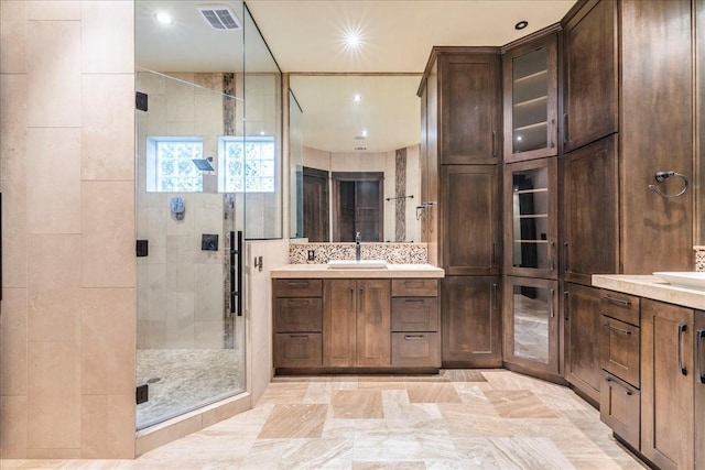 bathroom featuring tasteful backsplash, vanity, and a shower with door