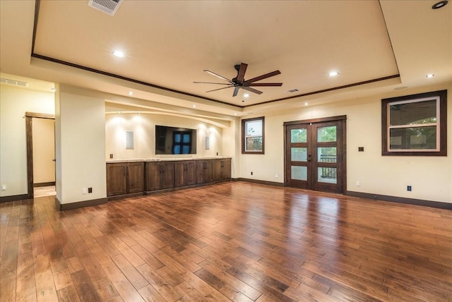 unfurnished living room with dark wood-type flooring, a raised ceiling, and french doors