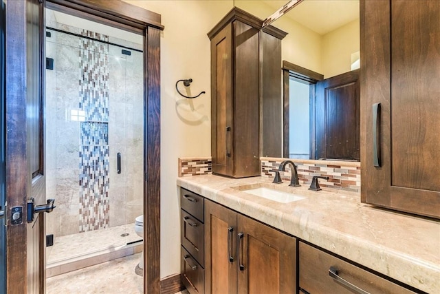 bathroom featuring tasteful backsplash, vanity, toilet, and tiled shower