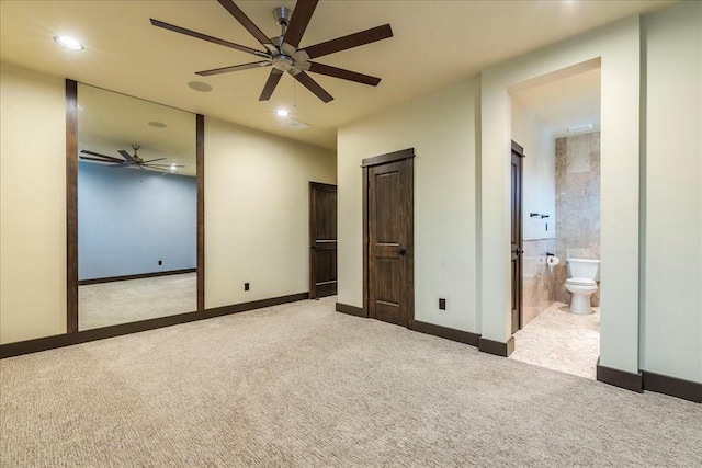 unfurnished bedroom featuring light carpet, ceiling fan, and ensuite bathroom