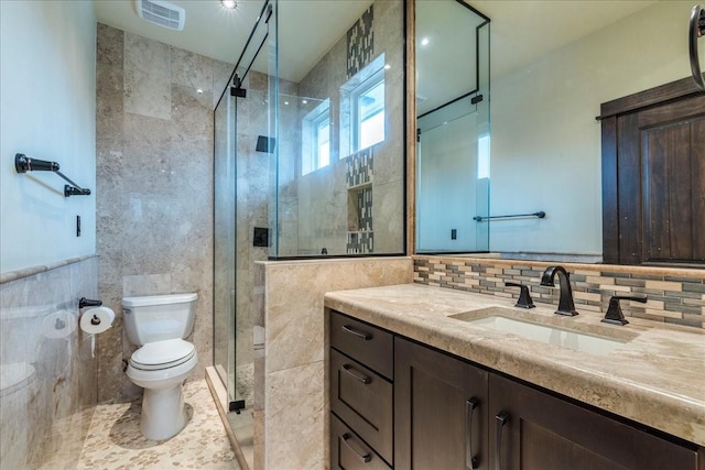 bathroom featuring vanity, a shower with shower door, tile walls, and toilet