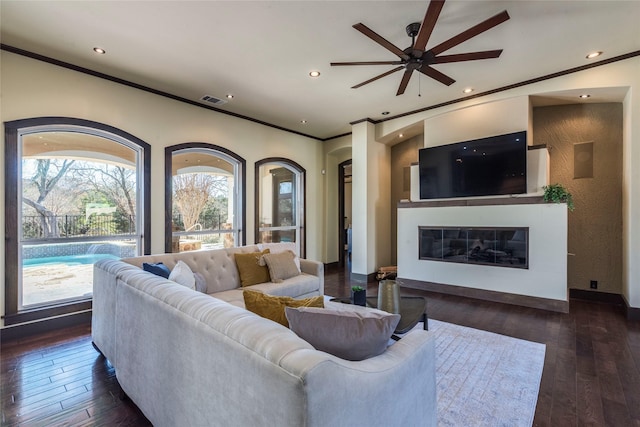 living room with crown molding, dark hardwood / wood-style floors, and ceiling fan