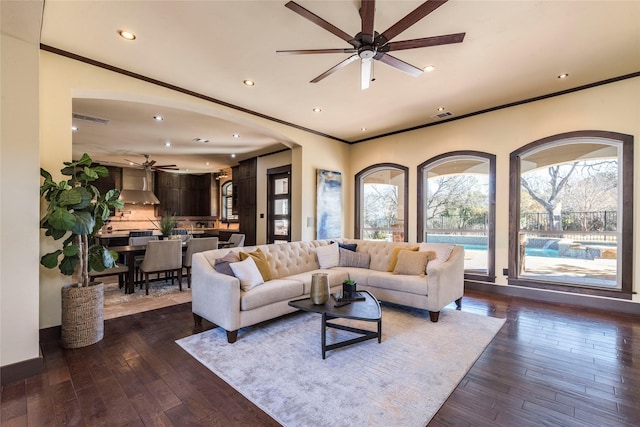 living room featuring ceiling fan, ornamental molding, and dark hardwood / wood-style floors