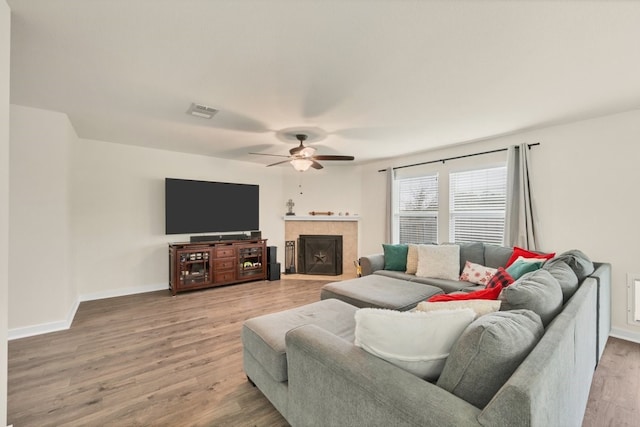 360 Gina Dr, Kyle, TX 78640 - living room featuring ceiling fan, light wood-style floors, baseboards, and a tiled fireplace